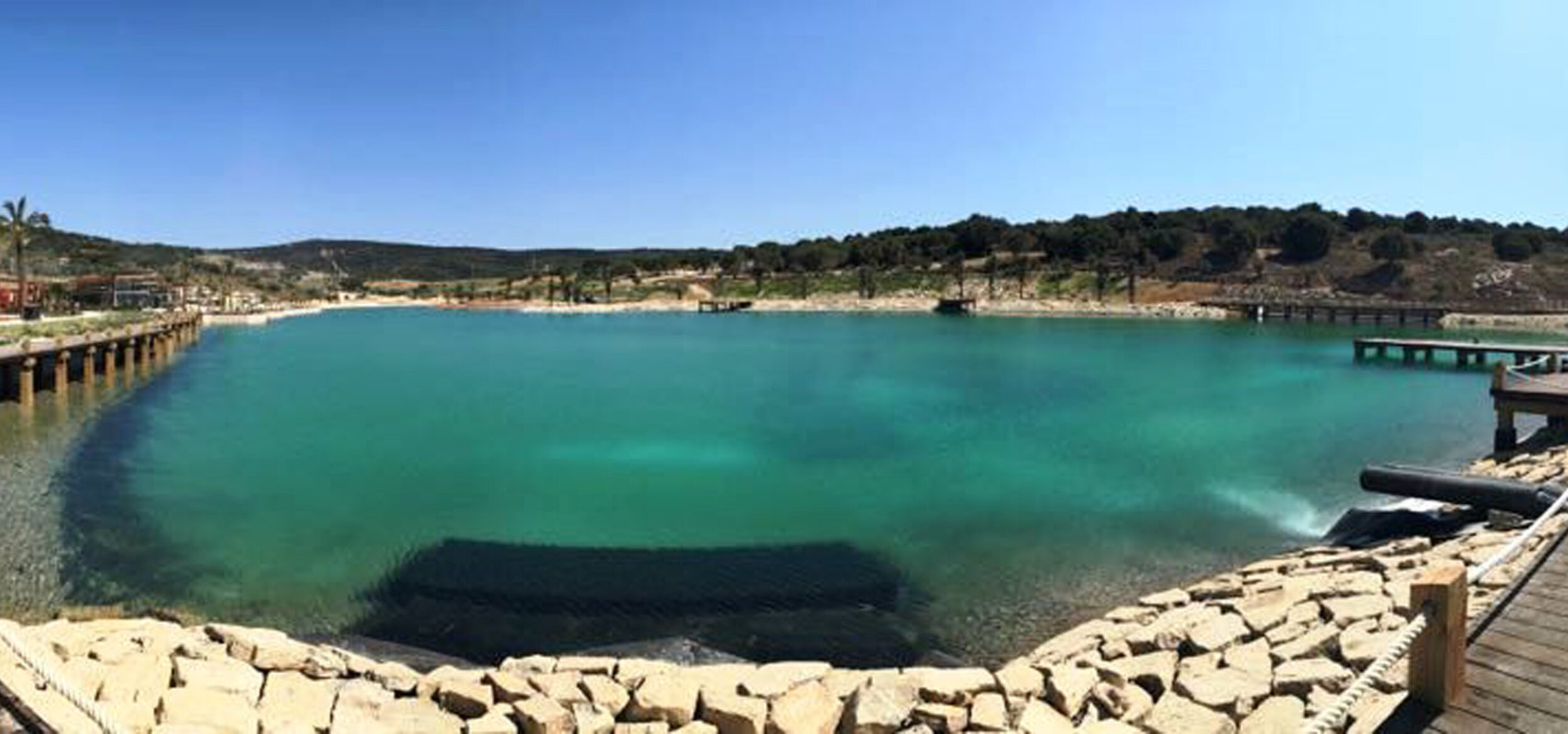 Blick über die Wasserfläche mit Balena-System des Spain Beach Club” in Sotogrande, im Hintergrund eine Hügellandschaft