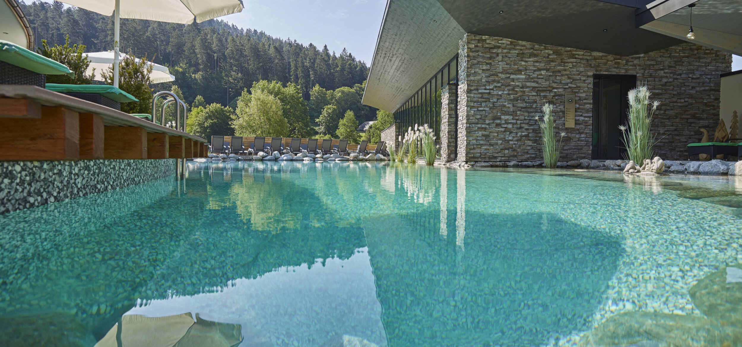 Blick vom Balena-Schwimmteich auf das Wellnesshotel „Heselbacher Hof” in Baiersbronn